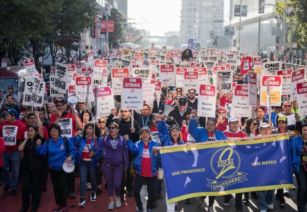 Photo of the march, featuring signs that say 'One Job Should Be Enough Photo of the march, featuring signs that say 'One Job Should Be Enough