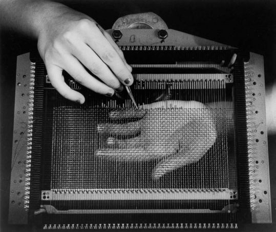 A hand holding an instrument over a weaving mesh an another hand underneath. A hand holding an instrument over a weaving mesh an another hand underneath.