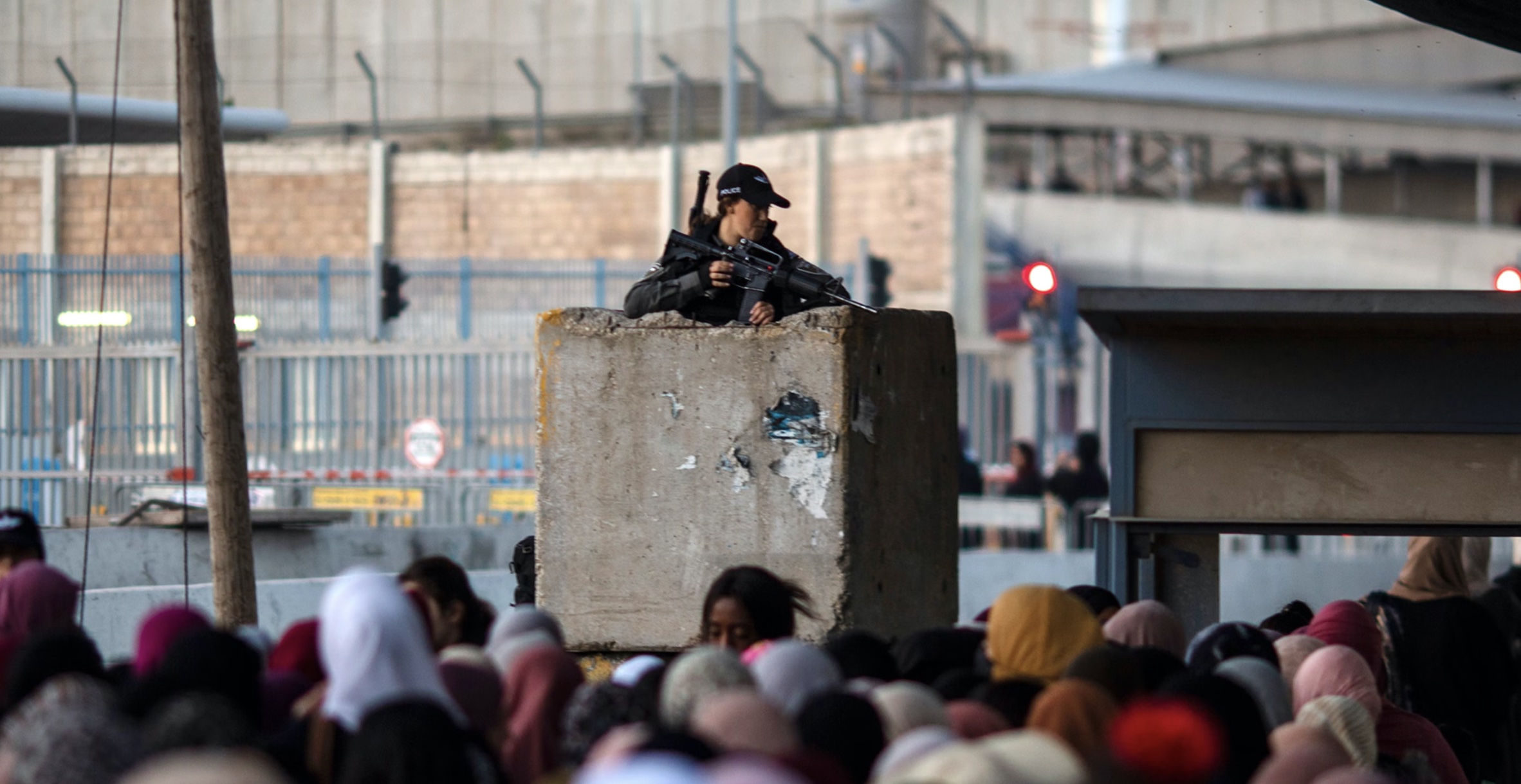 An Israeli border police stands guard as Palestinians make their way through Qalandia checkpoint An Israeli border police stands guard as Palestinians make their way through Qalandia checkpoint