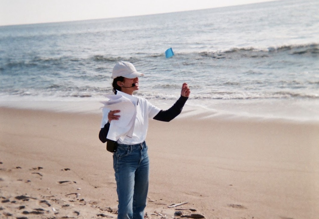 Image of a person at a beach holding up a blue flag in one hand Image of a person at a beach holding up a blue flag in one hand