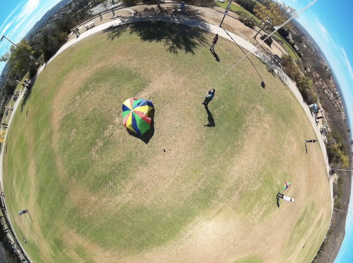 A group becomes invisible to the camera by huddling under a colored parachute. A group becomes invisible to the camera by huddling under a colored parachute.