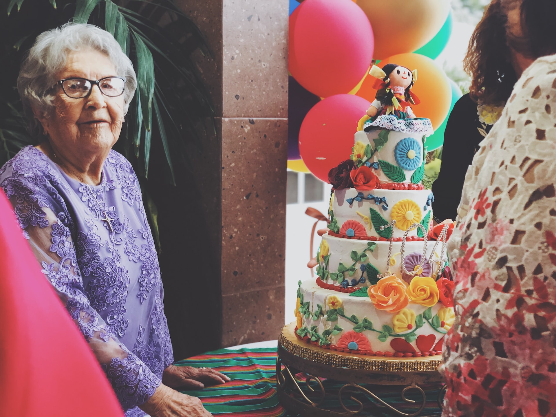 A woman wearing purple floral long-sleeved dress besides 4-layer cake photo A woman wearing purple floral long-sleeved dress besides 4-layer cake photo
