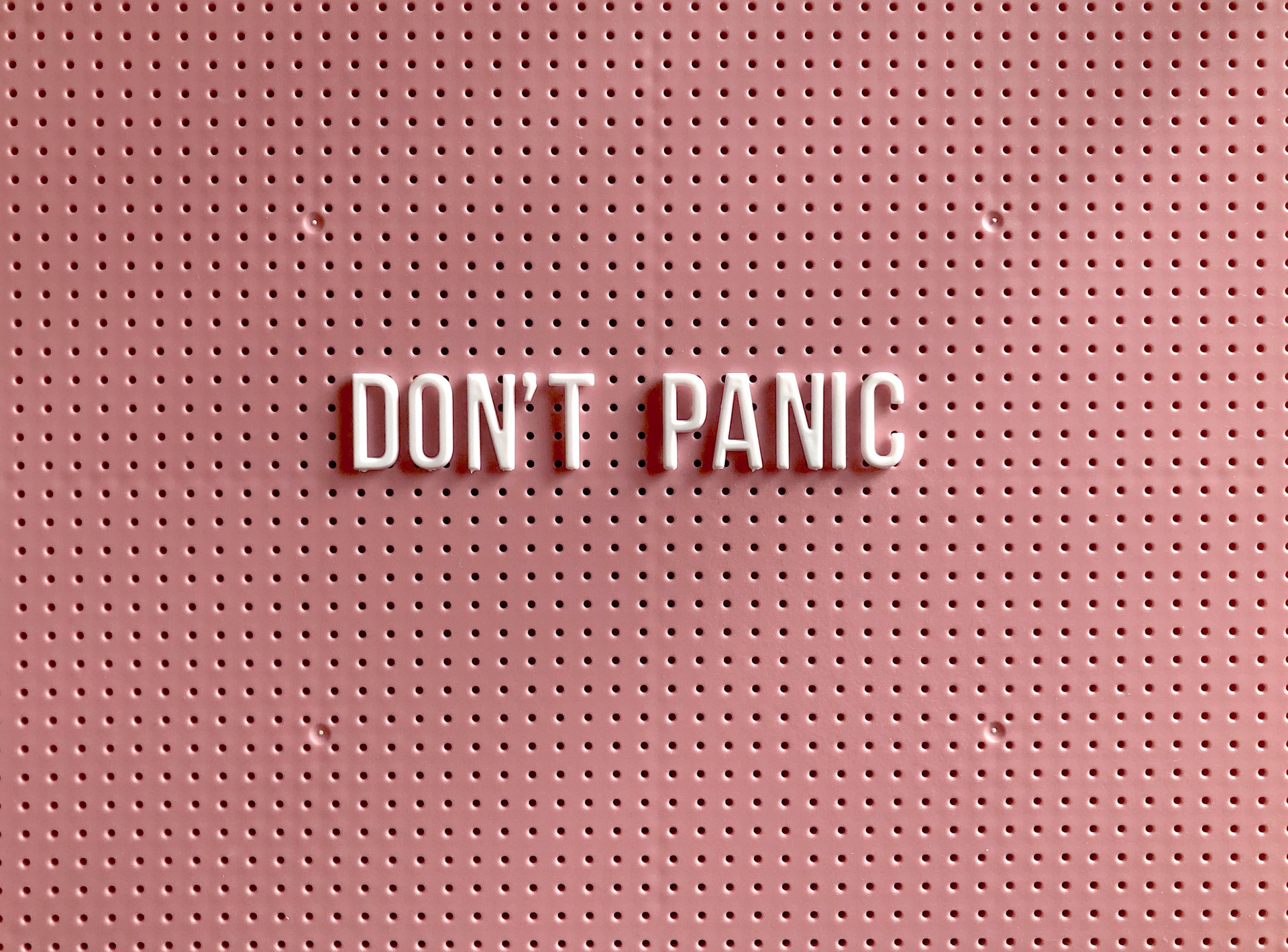 White letters on a board colored millennial pink that say DON'T PANIC White letters on a board colored millennial pink that say DON'T PANIC